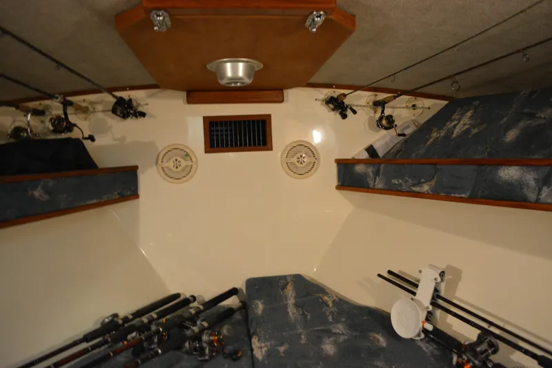 Slide: The Image of 2004 Carolina Classic 28 boat interior with fishing rods and storage shelves. - 40