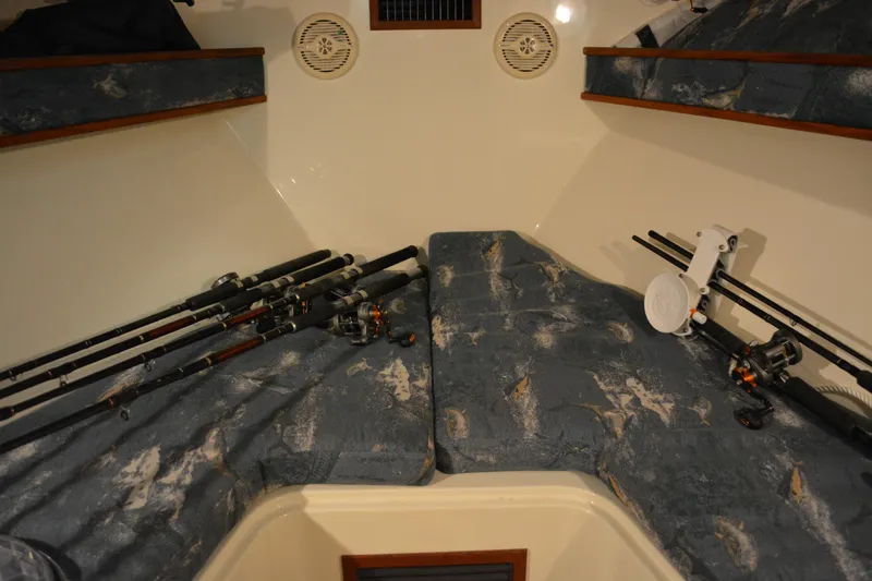 Slide: The Image of 2004 Carolina Classic 28 cabin interior with fishing rods and blue patterned cushions. - 42