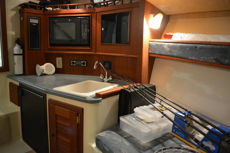 Slide: The Image of 2004 Carolina Classic 28 cabin interior with kitchenette, fishing rods, and storage. - 45
