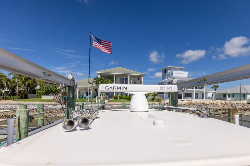Slide: The Image of 2022 Grady-White Canyon 336 boat docked, American flag, clear sky, waterfront property. - 32