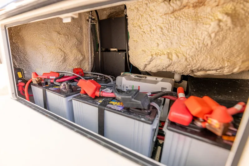 Slide: The Image of Battery compartment of 2022 Grady-White Canyon 336 boat, featuring multiple batteries and wiring. - 48