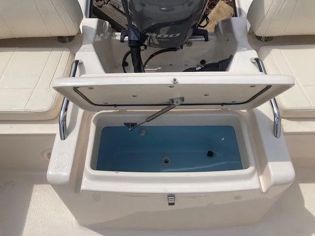 Slide: The Image of 2022 Grady-White Freedom 215 boat with open storage compartment and visible engine. - 6
