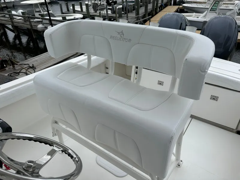 Slide: The Image of 2020 Regulator 23 Forward Seating boat with white cushioned helm seat at marina. - 4