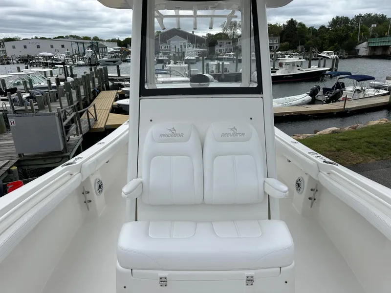 Slide: The Image of 2020 Regulator 23 Forward Seating boat at marina, featuring white cushioned seats. - 5