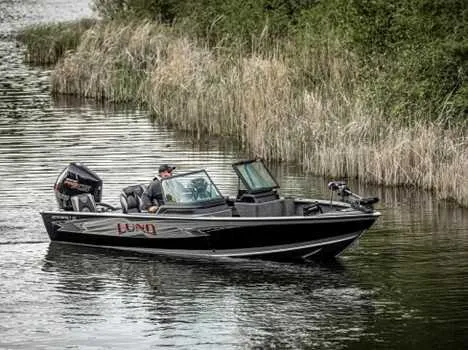 Slide: The Image of 2026 Lund 2075 IMPACT XS boat cruising on a calm river surrounded by reeds. - 13