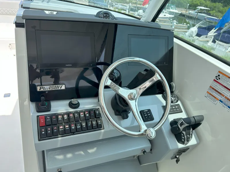 Slide: The Image of 2026 Pursuit DC 326 boat dashboard with steering wheel and control panels. - 14