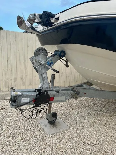 Slide: The Image of 2022 Bayliner DX2000 boat on trailer, parked on gravel near wooden fence. - 8