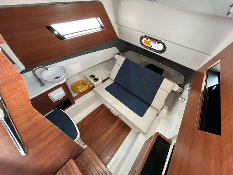 Slide: The Image of 2026 Pursuit S 328 cabin interior with wood accents, seating, and sink. - 18