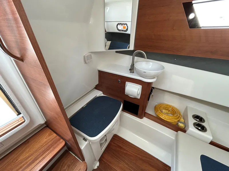 Slide: The Image of 2026 Pursuit S 328 boat interior bathroom with wood accents, sink, and toilet. - 19