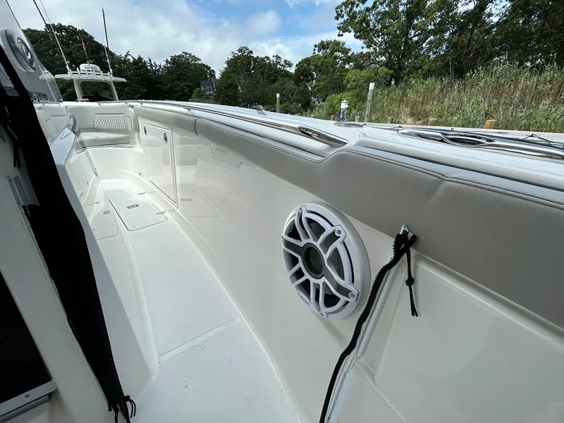 Slide: The Image of 2026 Pursuit S 328 boat interior with speaker, white seating, and lush greenery background. - 20