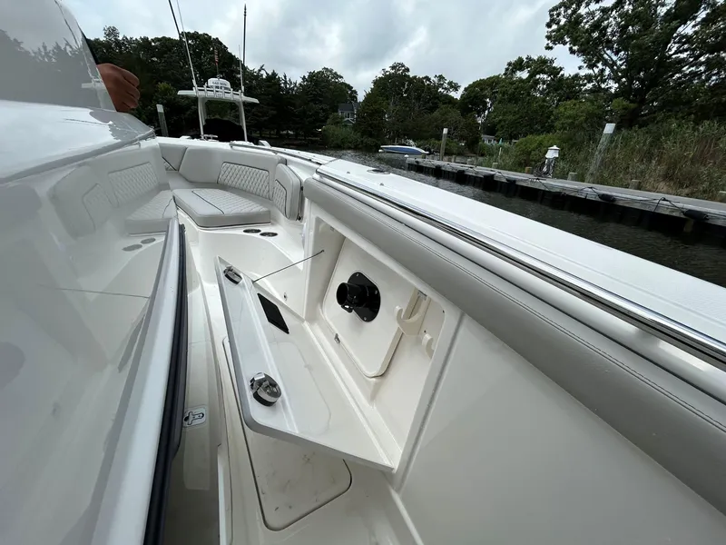 Slide: The Image of 2026 Pursuit S 328 boat interior with seating and storage, docked near lush greenery. - 23