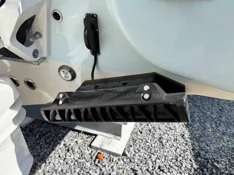 Slide: The Image of 2024 Key West 263 FS boat transom detail with mounted equipment on gravel surface. - 8