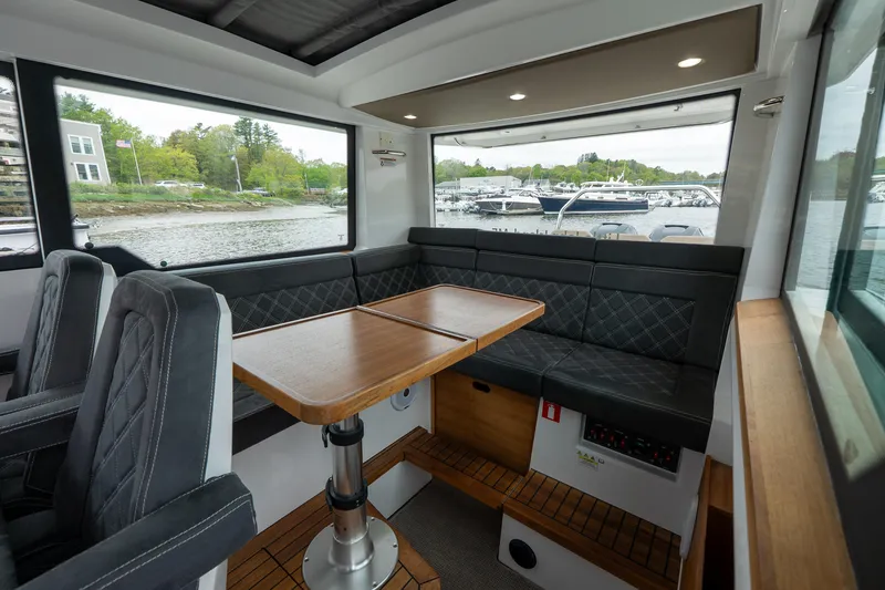 Slide: The Image of Interior of 2019 Axopar 37 Cabin with seating and table, overlooking marina. - 22
