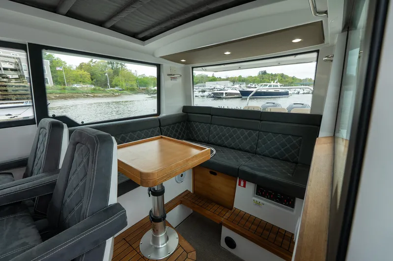 Slide: The Image of Interior of 2019 Axopar 37 Cabin with seating and table, overlooking marina. - 23