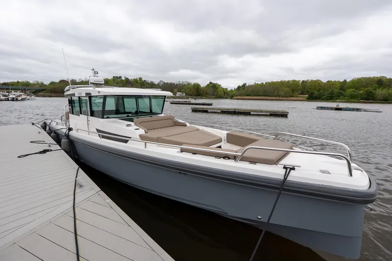 Slide: The Image of 2019 Axopar 37 Cabin boat docked on a calm lake under cloudy skies. - 3