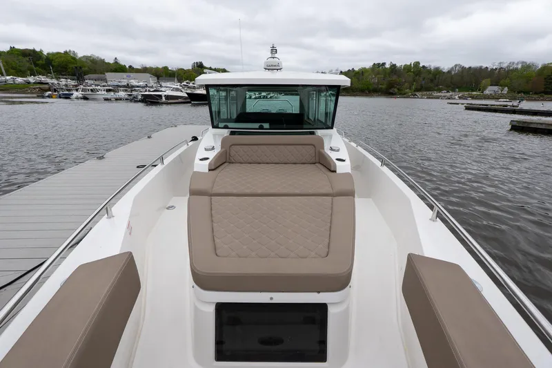 Slide: The Image of 2019 Axopar 37 Cabin boat with beige seating, docked on a calm lake. - 7