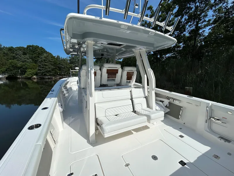 Slide: The Image of 2026 Pursuit S 358 boat interior with seating, rod holders, and canopy, docked by lush greenery. - 4