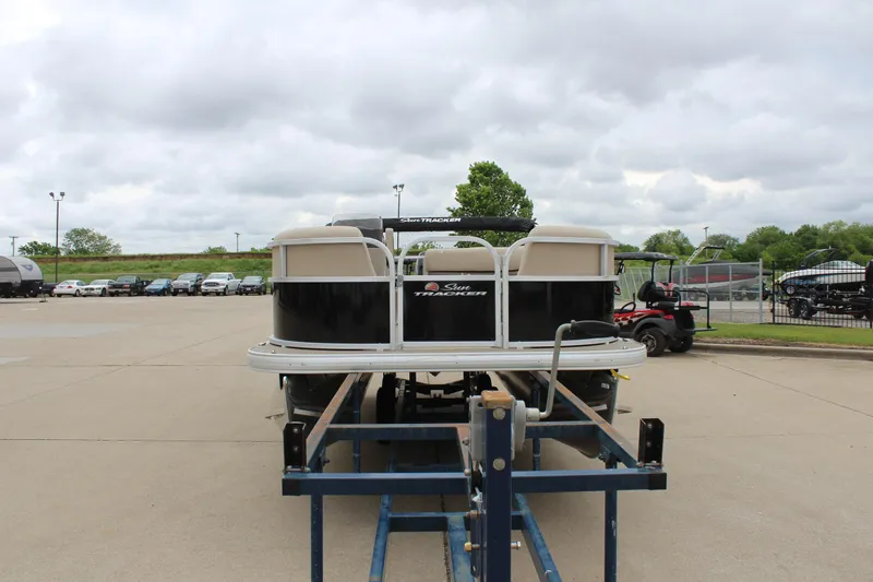 Slide: The Image of 2025 Sun Tracker Party Barge 16 DLX on trailer, parked outdoors under cloudy sky. - 6
