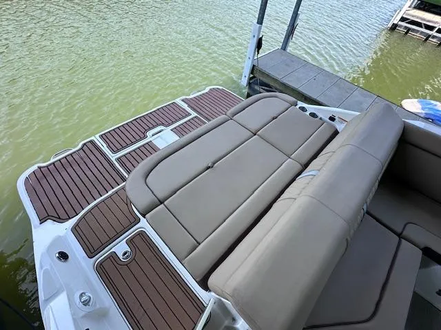 Slide: The Image of 2016 Sea Ray 270 Sundeck boat with spacious seating and wooden deck by the water. - 14