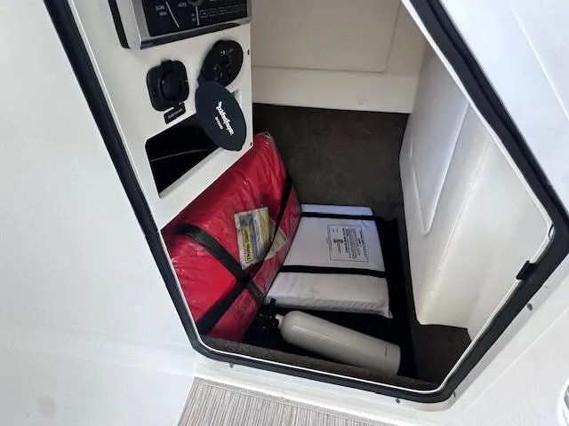Slide: The Image of Storage compartment in a 2016 Sea Ray 270 Sundeck with safety equipment and accessories. - 25