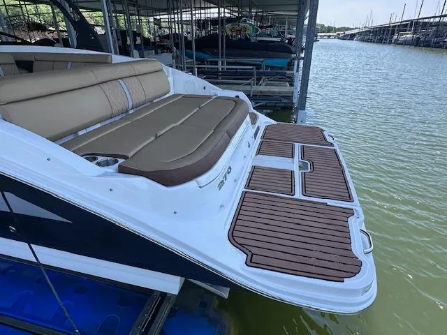 Slide: The Image of 2016 Sea Ray 270 Sundeck with spacious seating and elegant wood deck, docked by the water. - 8