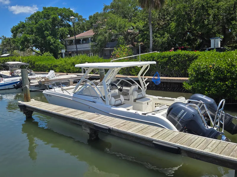 The Image of 2021 World Cat 255C boat docked by lush greenery and waterfront homes. - 0