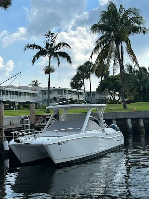 Slide: The Image of 2021 World Cat 255C boat docked by palm trees and waterfront homes. - 20