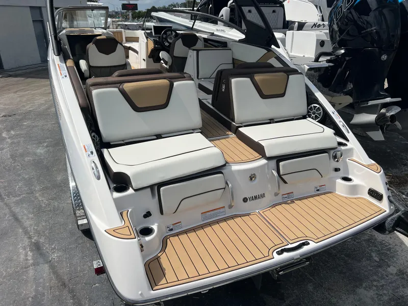 Slide: The Image of 2021 Yamaha Boats 252SE with luxurious seating and sleek design, docked outdoors. - 15