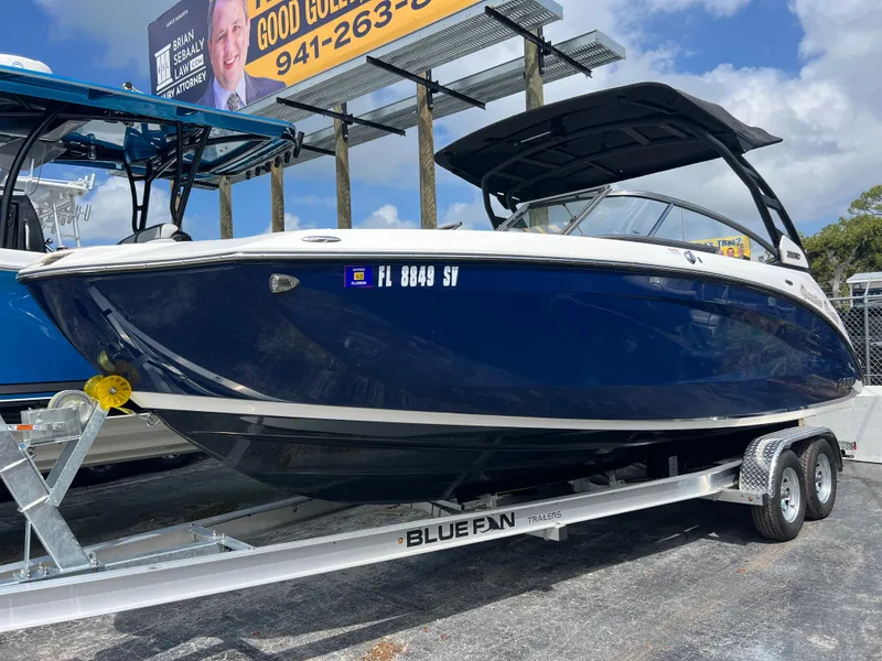 Slide: The Image of 2021 Yamaha Boats 252SE on trailer, blue hull, parked outdoors. - 2