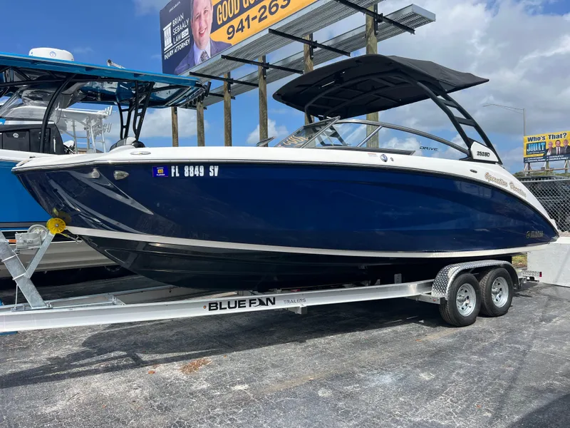 Slide: The Image of 2021 Yamaha Boats 252SE on trailer, blue hull, parked outdoors under a clear sky. - 3