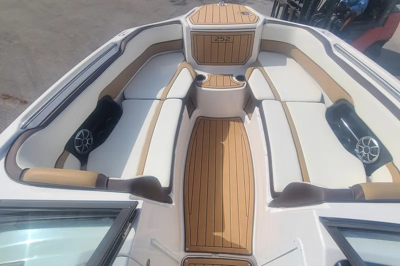 Slide: The Image of 2021 Yamaha Boats 252SE interior with tan and white seating, wood accents, and speakers. - 35