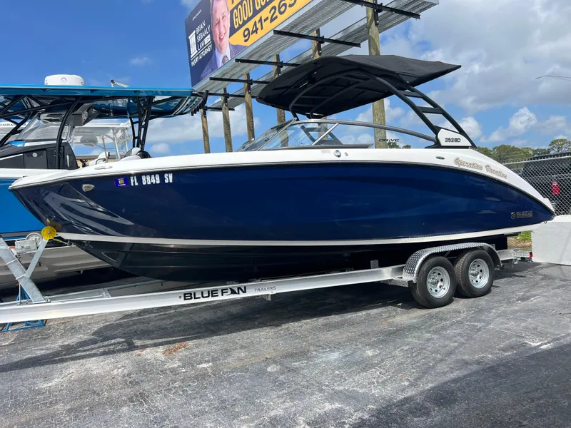 Slide: The Image of 2021 Yamaha Boats 252SE on trailer, blue hull, parked outdoors. - 4