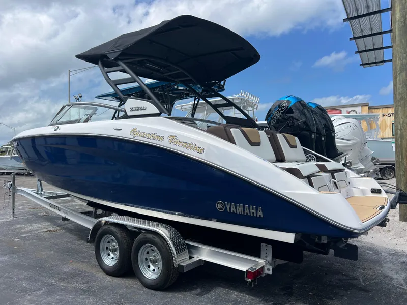 Slide: The Image of 2021 Yamaha Boats 252SE on trailer, blue and white design, under a cloudy sky. - 5