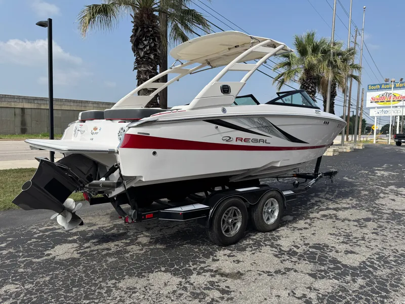 Slide: The Image of 2020 Regal LS2 Surf boat on trailer, parked near palm trees, sunny day. - 1