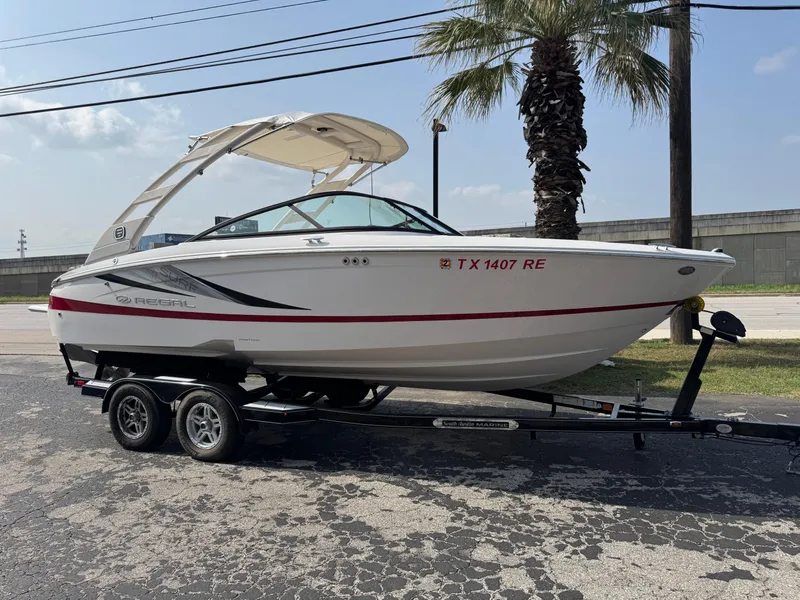 Slide: The Image of 2020 Regal LS2 Surf boat on trailer, parked near palm tree. - 22