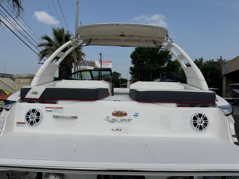 Slide: The Image of 2020 Regal LS2 Surf boat, rear view with speakers and seating, under a clear sky. - 8