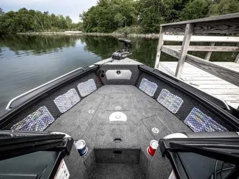 Slide: The Image of 2026 Lund 2075 Tyee boat interior with spacious deck and storage, docked by a serene lake. - 7