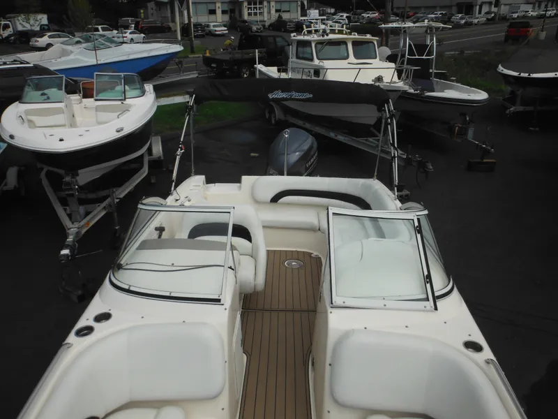 Slide: The Image of 2007 Hurricane SD 237 boat with open deck and seating, parked among other boats. - 48