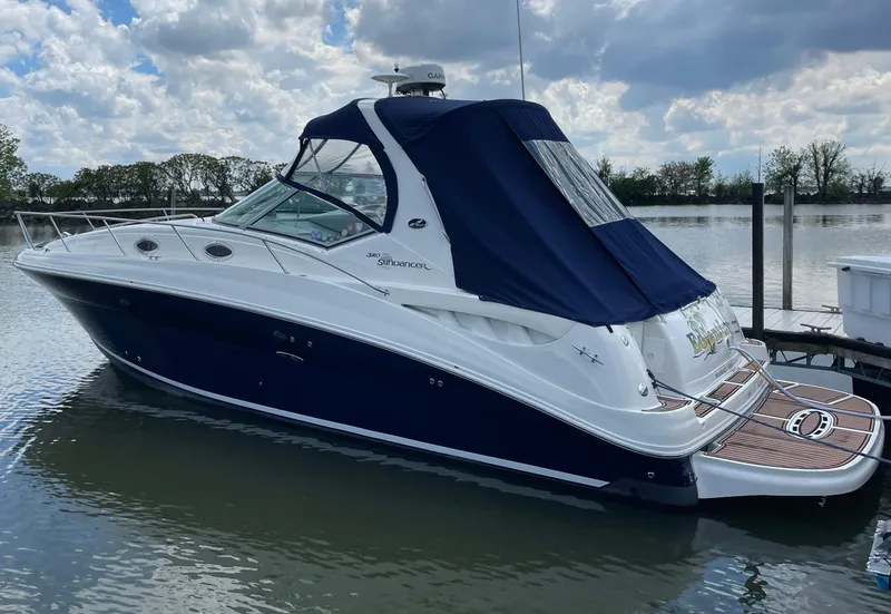 Slide: The Image of 2004 Sea Ray 320 Sundancer boat docked on calm water under cloudy sky. - 1