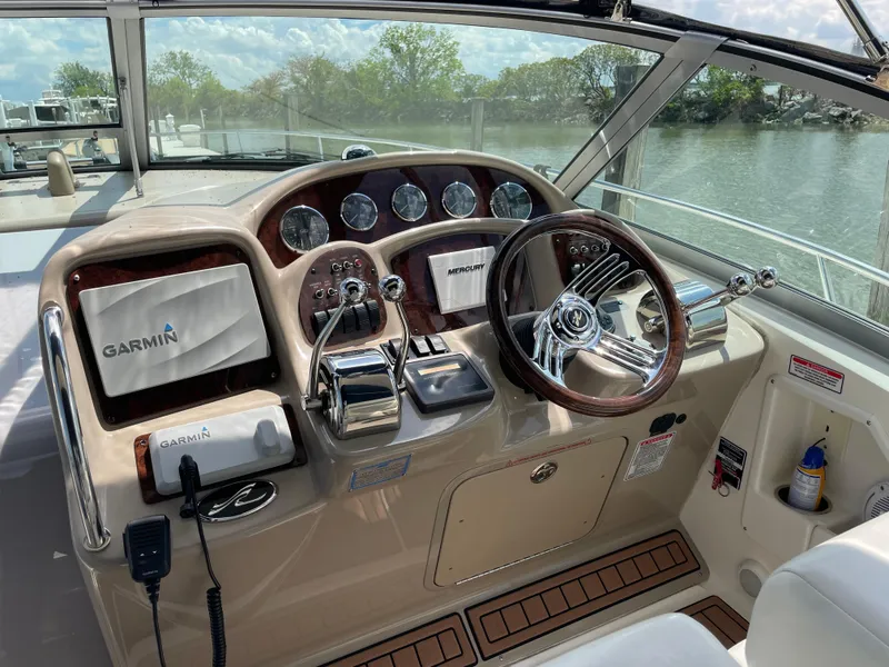Slide: The Image of 2004 Sea Ray 320 Sundancer helm with Garmin navigation, wood accents, and water view. - 2