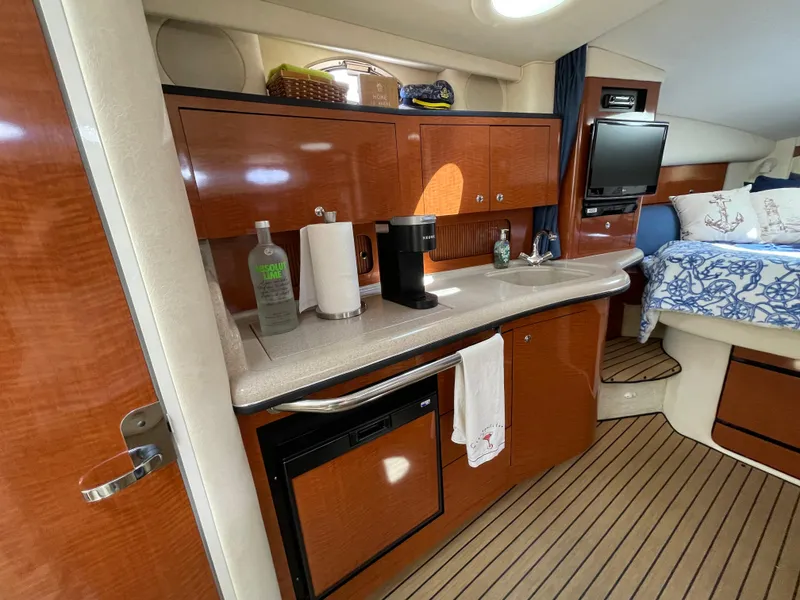 Slide: The Image of 2004 Sea Ray 320 Sundancer interior with kitchenette, wood cabinets, and cozy sleeping area. - 7