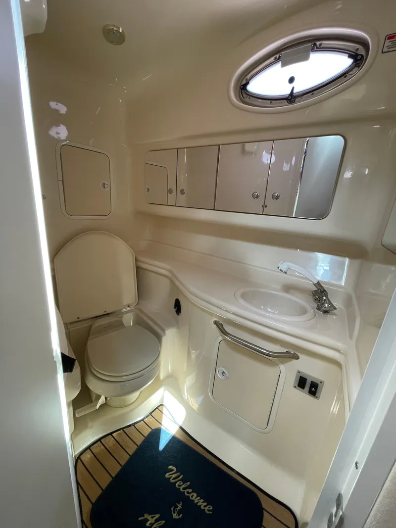 Slide: The Image of 2004 Sea Ray 320 Sundancer bathroom with toilet, sink, mirror, and porthole window. - 8