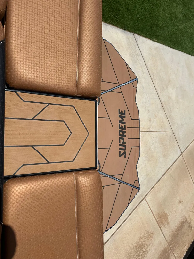 Slide: The Image of 2023 Supreme S220 boat interior with tan upholstery and branded flooring. - 11