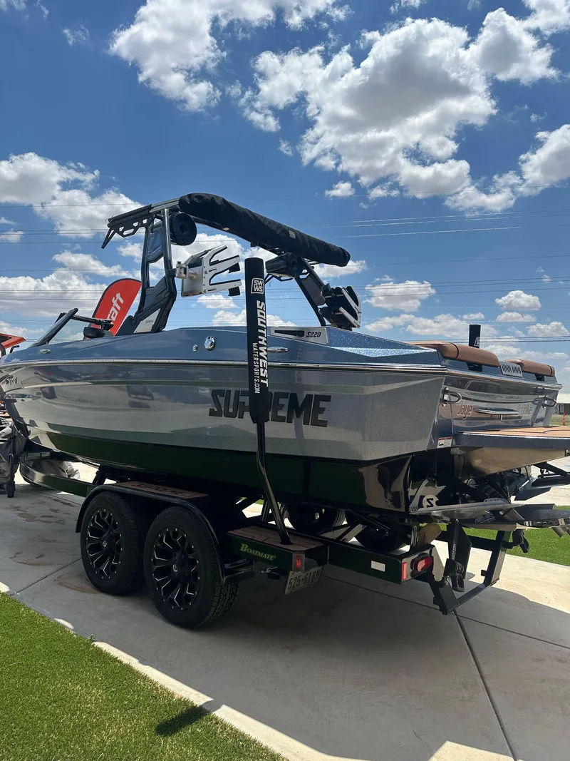 Slide: The Image of 2023 Supreme S220 boat on trailer under a blue sky with clouds. - 13