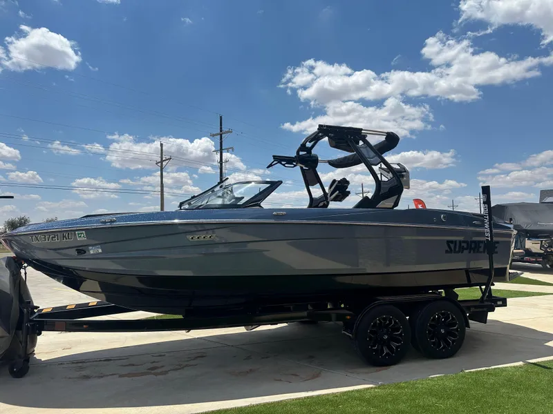 Slide: The Image of 2023 Supreme S220 boat on trailer under blue sky with clouds. - 3
