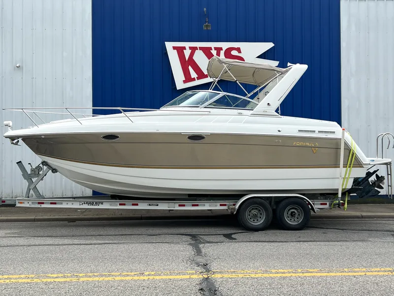 Slide: The Image of 2004 Formula 27 PC boat on trailer, parked outside a building with blue and white siding. - 0