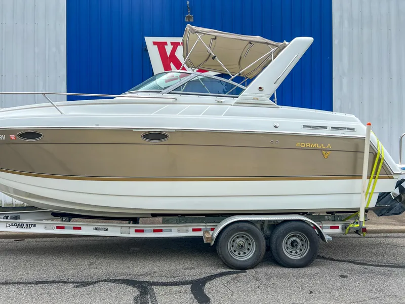 Slide: The Image of 2004 Formula 27 PC boat on trailer, beige and white, parked near blue and white building. - 3