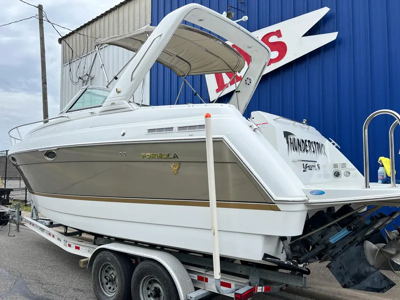 Slide: The Image of 2004 Formula 27 PC boat on trailer, parked near a blue building. - 5