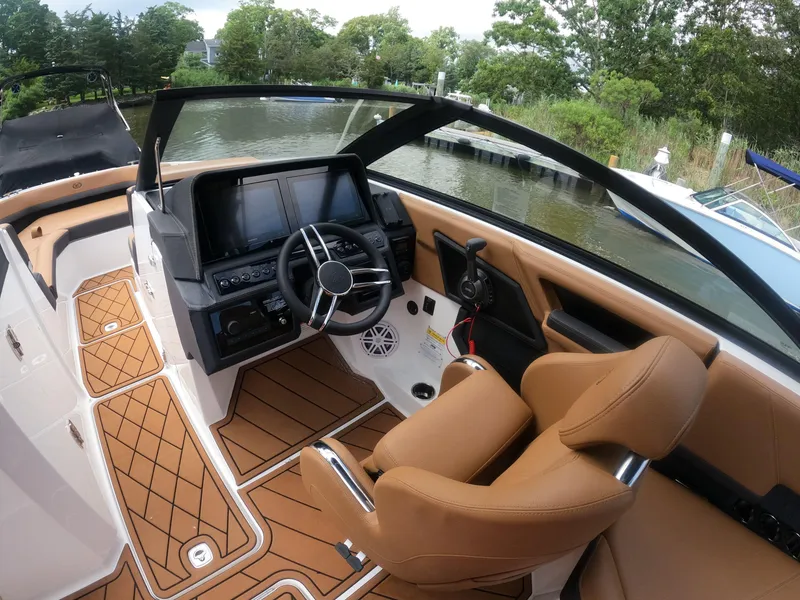 Slide: The Image of 2026 Cobalt R6 boat interior with tan seating, modern dashboard, and scenic waterway view. - 14