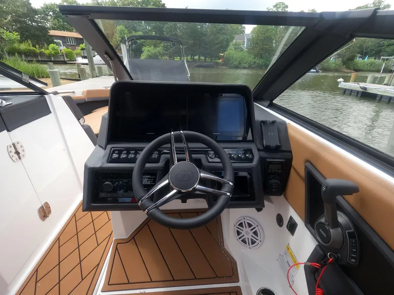 Slide: The Image of 2026 Cobalt R6 boat cockpit with steering wheel and control panel, docked by a scenic waterfront. - 15
